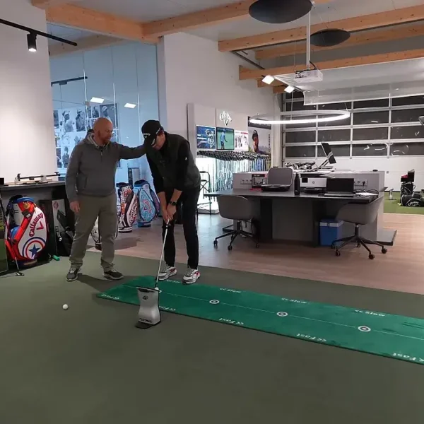 Fitter justiert die Körperhaltung des Spielers beim Putting‑Setup, Fokus auf Augenlinie und Ballposition