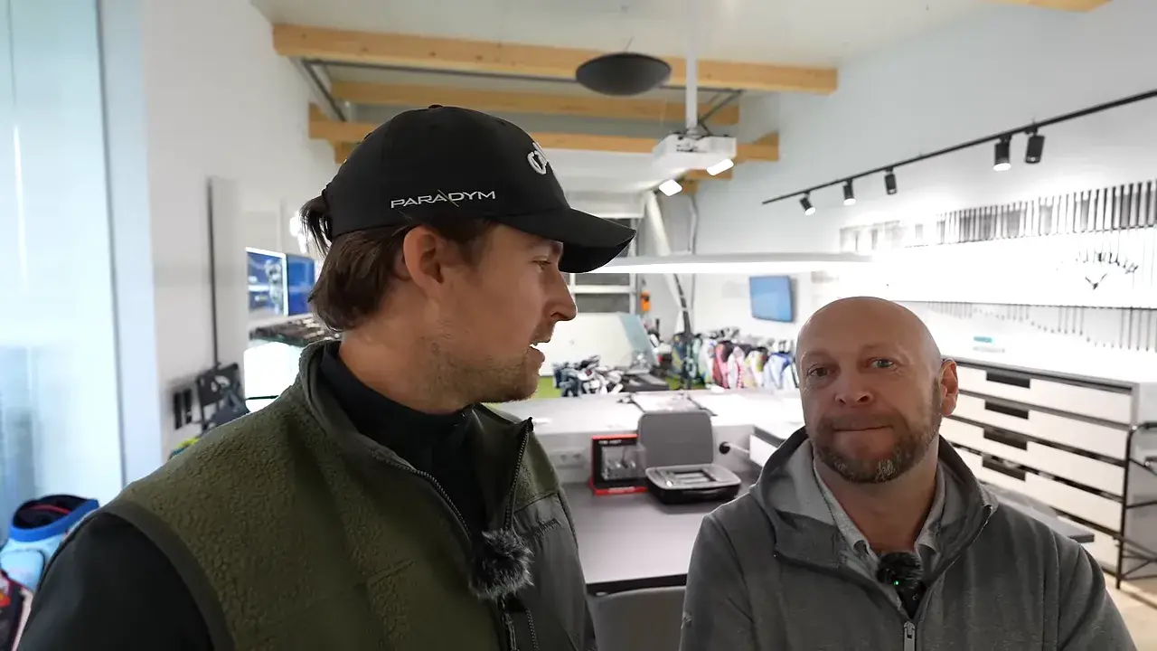 Putter Fitting: Schritt für Schritt zum stabileren Putt 2 Moderator und Fitter im Gespräch vor den Putter-Wänden im Studio