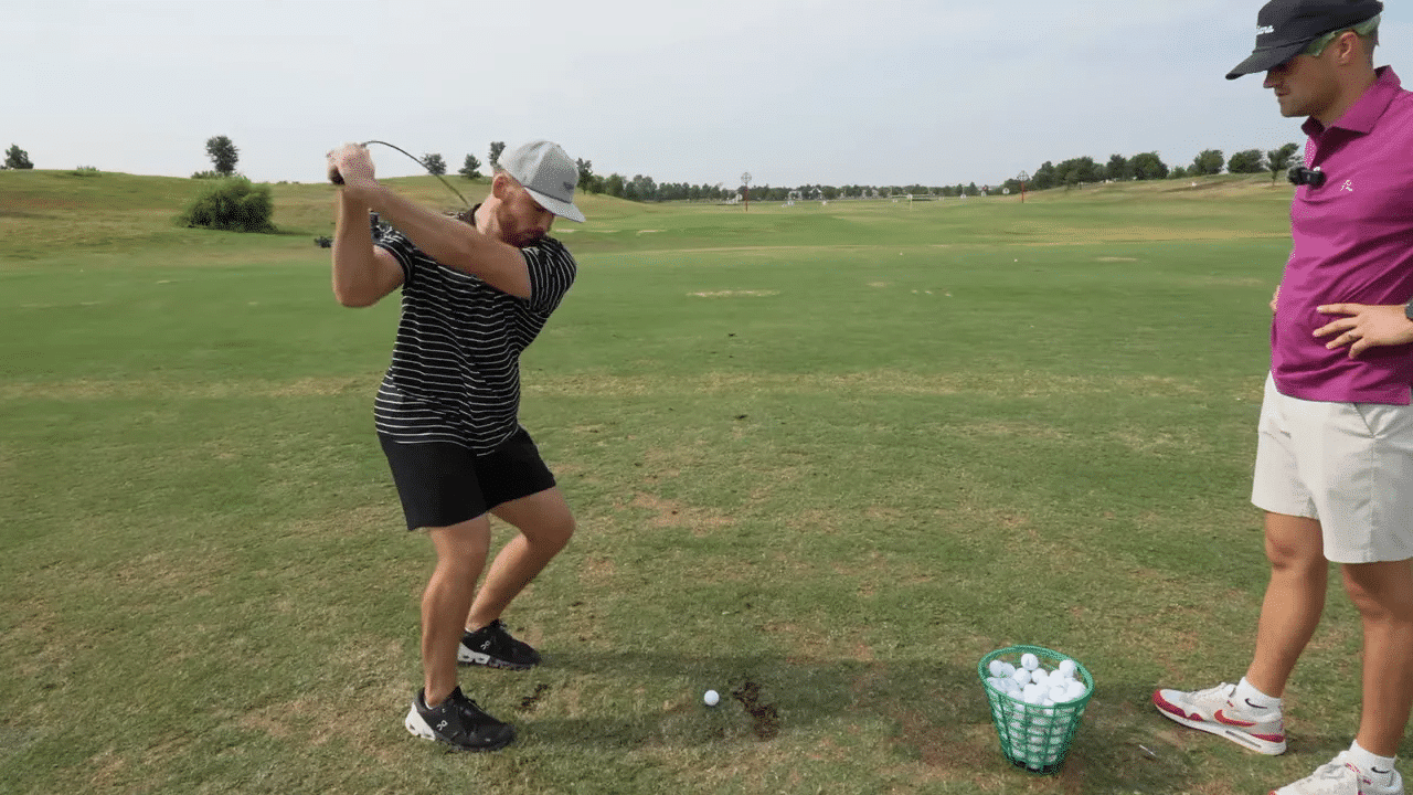 Golfer macht Schwung mit flexiblem Trainingsschläger auf der Driving Range neben einem Korb Bälle.