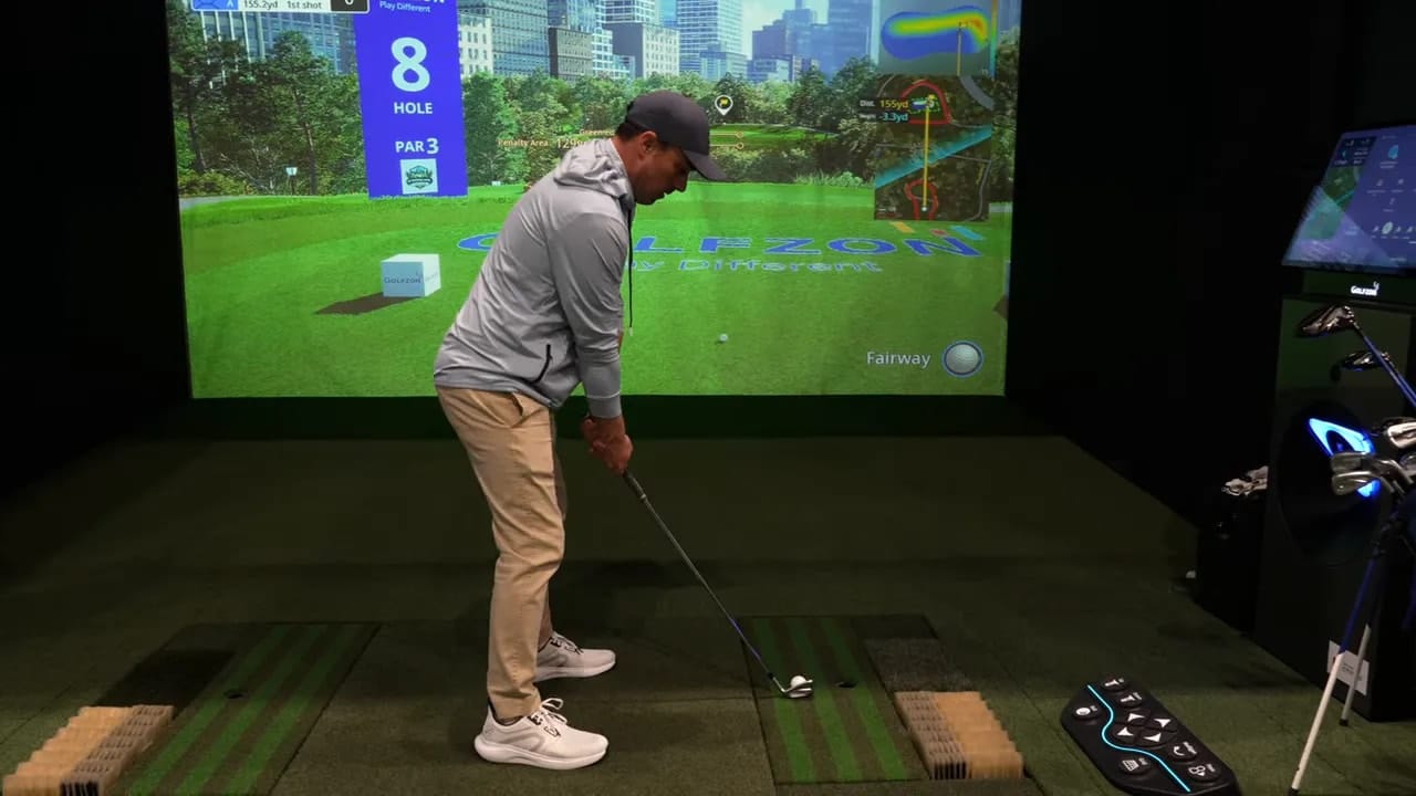 GOLFZON CityGolf Simulator: Spieler steht am Abschlag vor einer großen Simulatorprojektion mit deutlich lesbarem GOLFZON-Logo