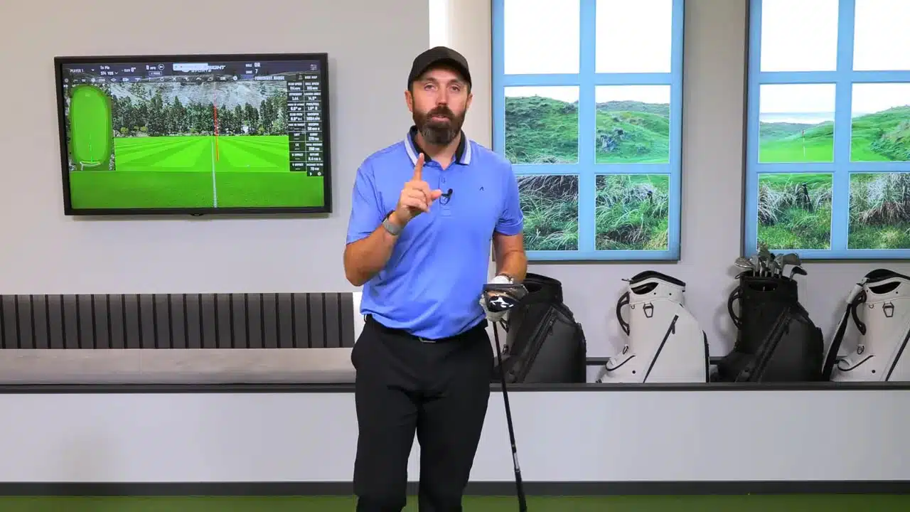 MIZUNO JPX ONE Driver: Ein ehrlicher Test, Technik, Zahlen und Urteil 5 Moderator zeigt den MIZUNO JPX ONE Driver frontal in der Kameraansprache, Studiohintergrund mit Bildschirm und Golfbags