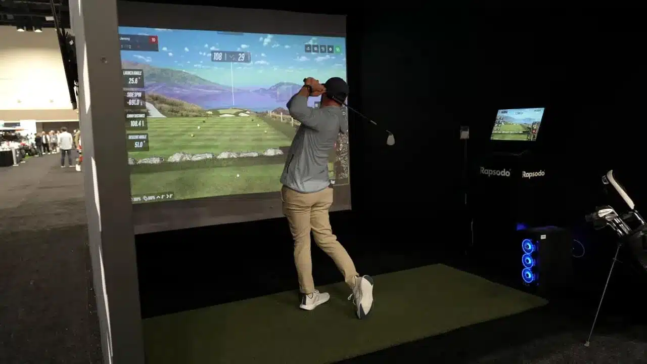 Goflprodukte 2026: 9 bahnbrechende Innovationen vom PGA Show Rückblick 7 Vollständiges Rapsodo-Heim-Simulator-Setup mit Leinwand, Spieler in Aktion und PC-Monitor