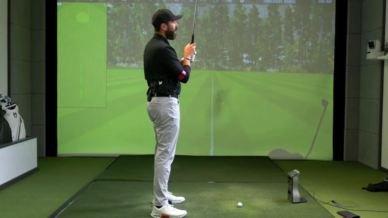 Seitenansicht eines Golfers im Indoor-Simulator mit TRS Slider am Oberarm und Gurt am Oberkörper