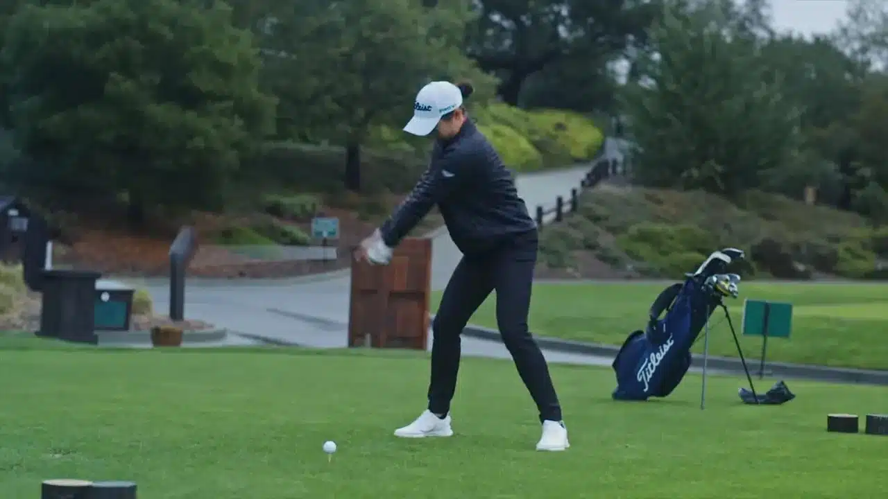 Wie verhalten sich Golfbälle bei Kälte? Erklärung, Einfluss auf Distanz und praktische Tipps 3 Golferin beim Addressing des Balls auf dem Tee mit Golfbag im Hintergrund