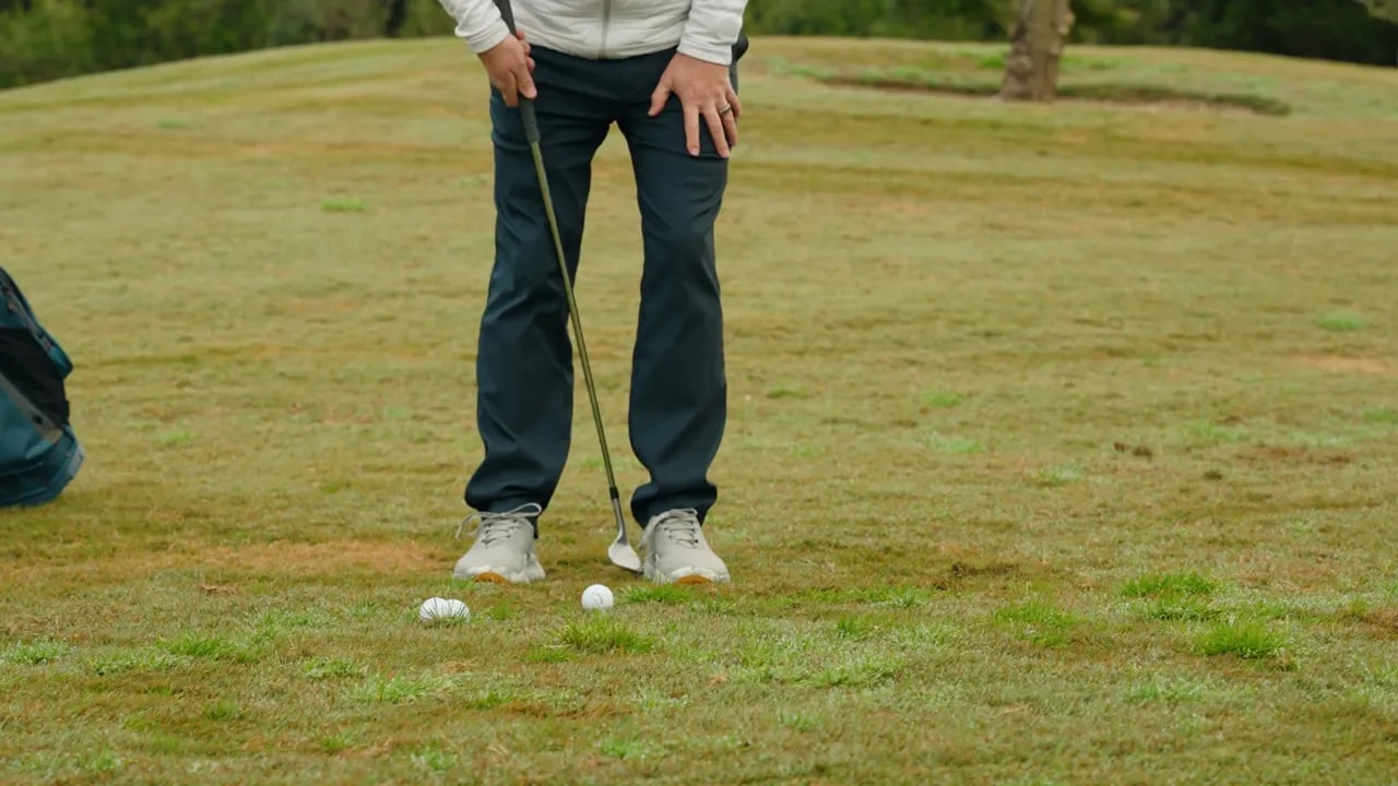 Beine, Füße und Golfbälle in der Startposition zur Demonstration von Fuß- und Ballposition
